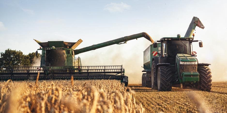 Mähdrescher und Traktor bei der Ernte auf einem Weizenfeld Mähdrescher und Traktor bei der Ernte auf einem Weizenfeld