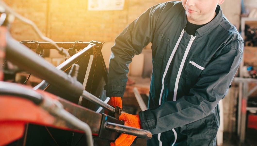 A mechanic is repairing a tractor used in agriculture. A mechanic is repairing a tractor used in agriculture.