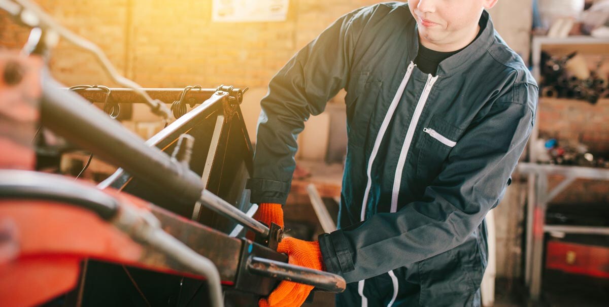 A mechanic is repairing a tractor used in agriculture. A mechanic is repairing a tractor used in agriculture.